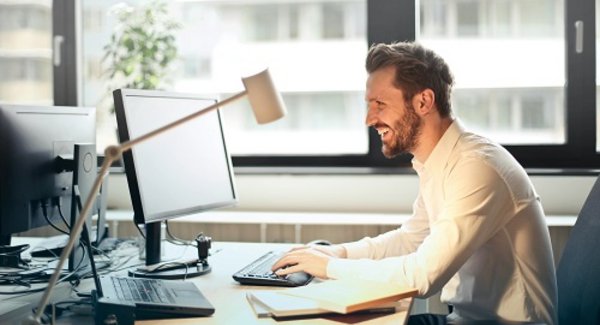 Junger Mann sitzt am Schreibtisch vor seinem Computer