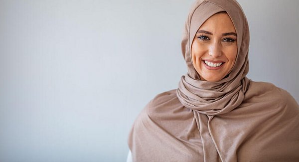 Eine junge Frau mit Kopftuch lächelt in die Kamera