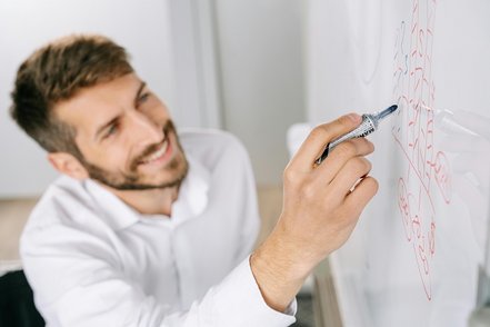 Junger Mann schreibt auf ein Flipchart.