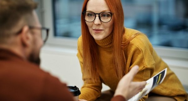 Eine Frau schaut einen gegenüber sitzenden Mann im Gespräch am.