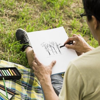 Ein Mann sitzt im Gras und zeichnet