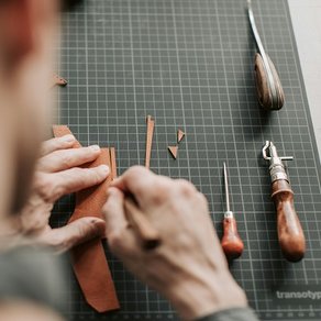 Ein Mann bearbeitet ein Stück Leder