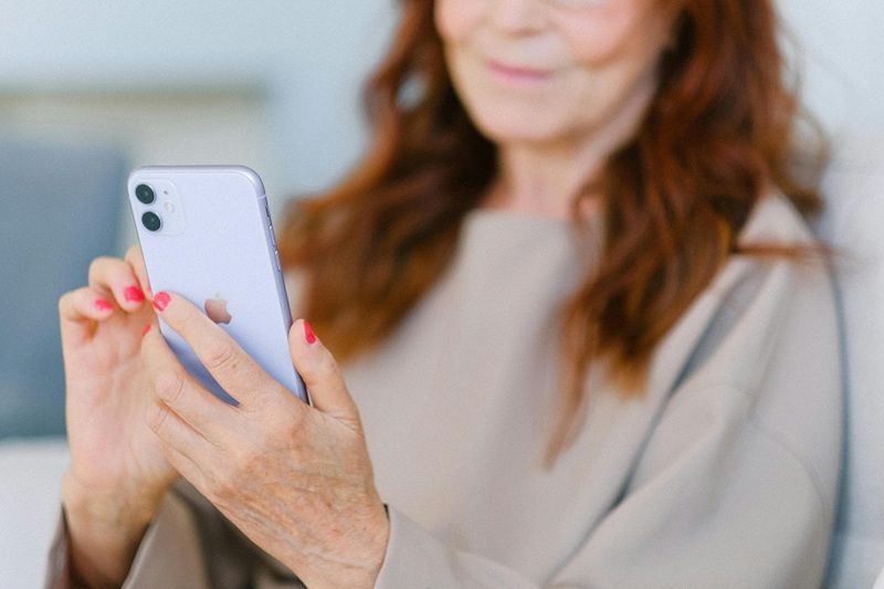 Eine &auml;ltere Dame h&auml;lt ein Iphone in der Hand.