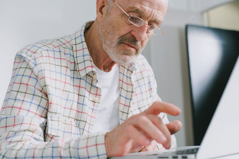 &Auml;lterer Herr sitzt vor dem Laptop.