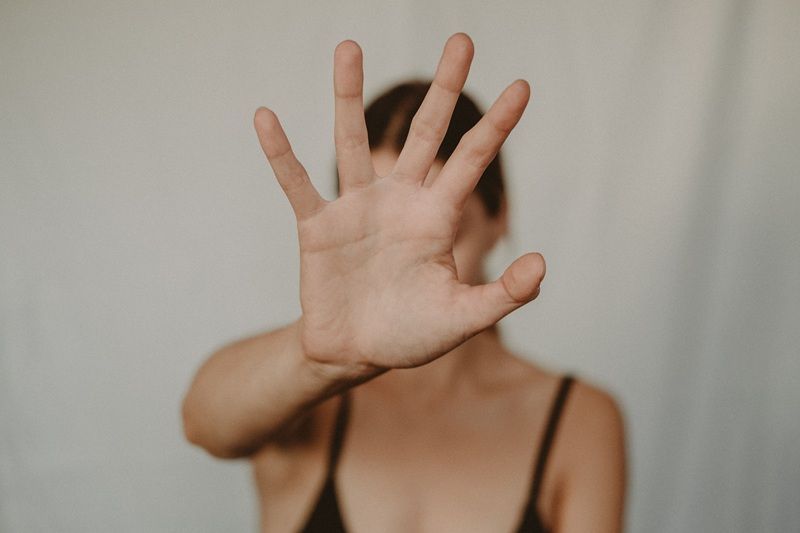 Eine Frau streckt ihre Hand abwehrend vor sich.
