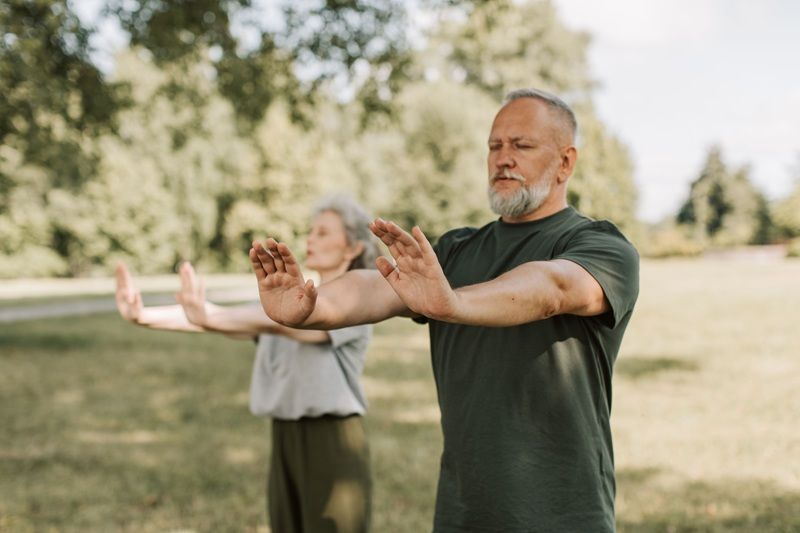 Eine Frau und ein Mann machen Qi Gong im Freien.
